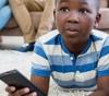 Boy watching TV with a remote control in his hand